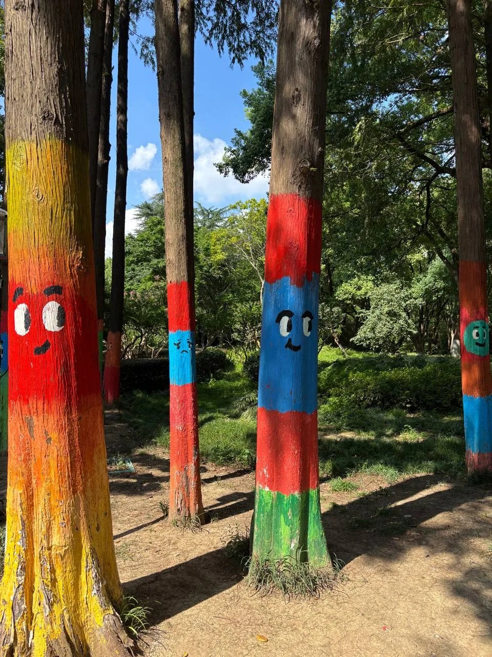 Tree trunks painted with colorful bands and cartoon faces.