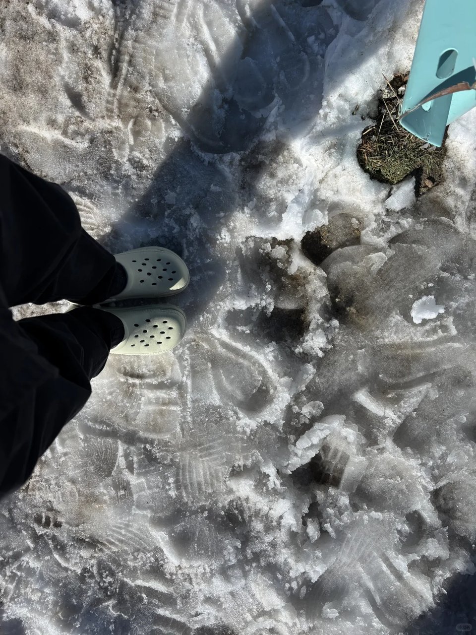 Feet in Crocs standing on packed snow and ice.