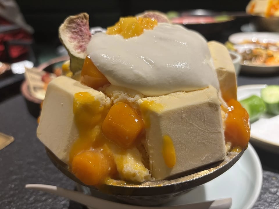 A mango dessert topped with cream and fruit.
