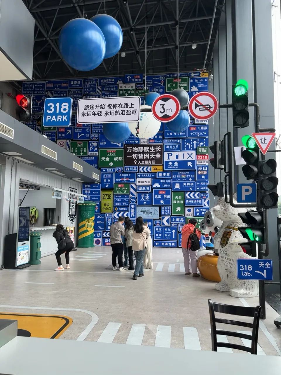 A road-sign themed hall at the Tianquan service area with G318 signs and traffic lights.