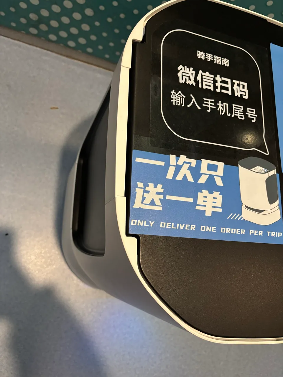 A delivery robot lid with a sign saying it delivers one order per trip.