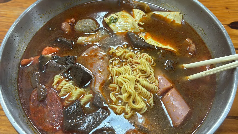 A bowl of spicy malatang with instant noodles, meatballs, and luncheon meat.