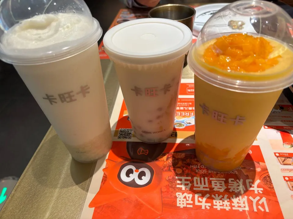 Three Kawangka milk tea and fruit drinks on a restaurant table.