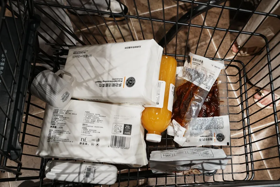 A shopping cart holding tissues, juice, and beef jerky.