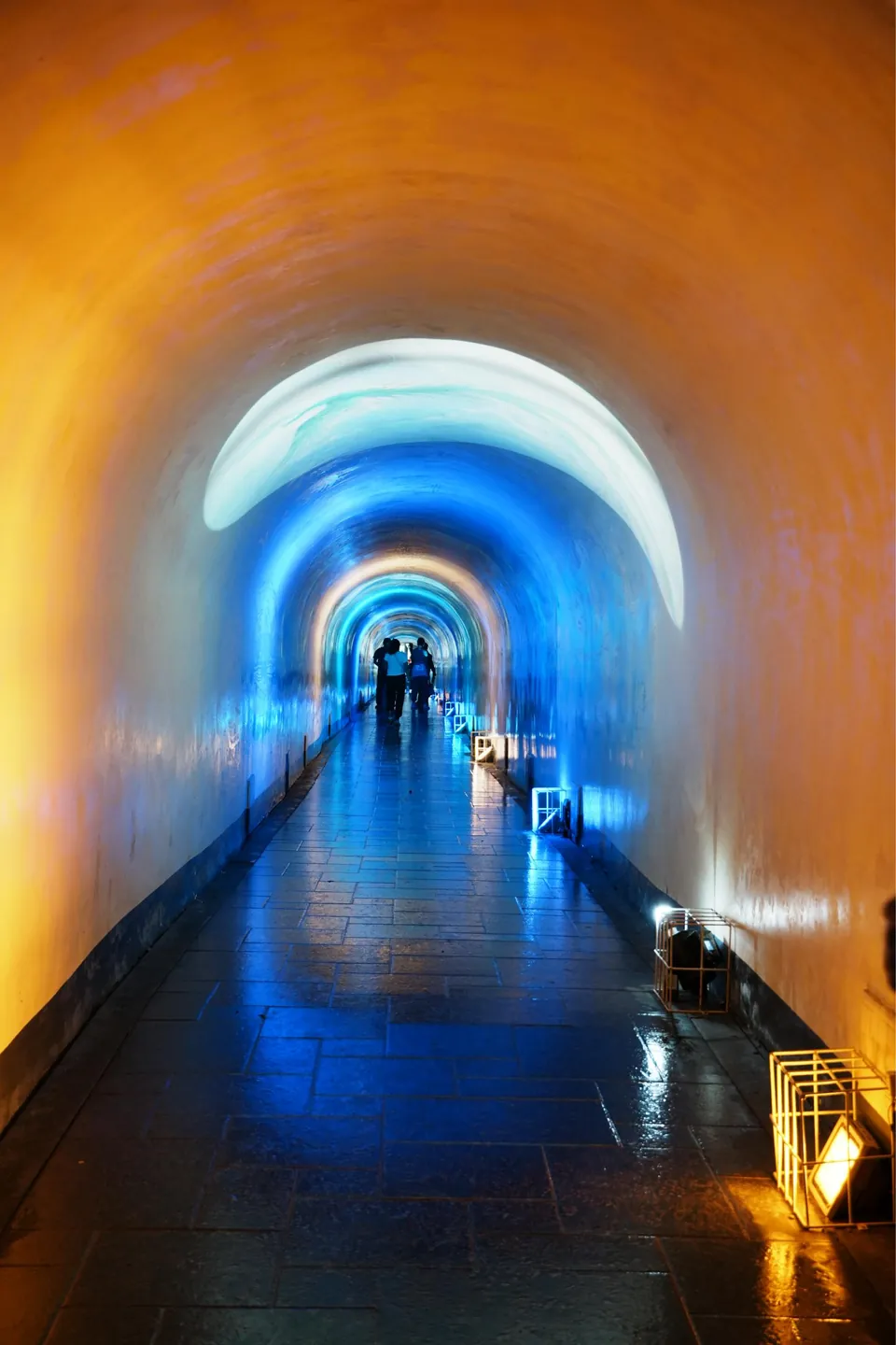 A tunnel walkway glowing in blue and orange light.