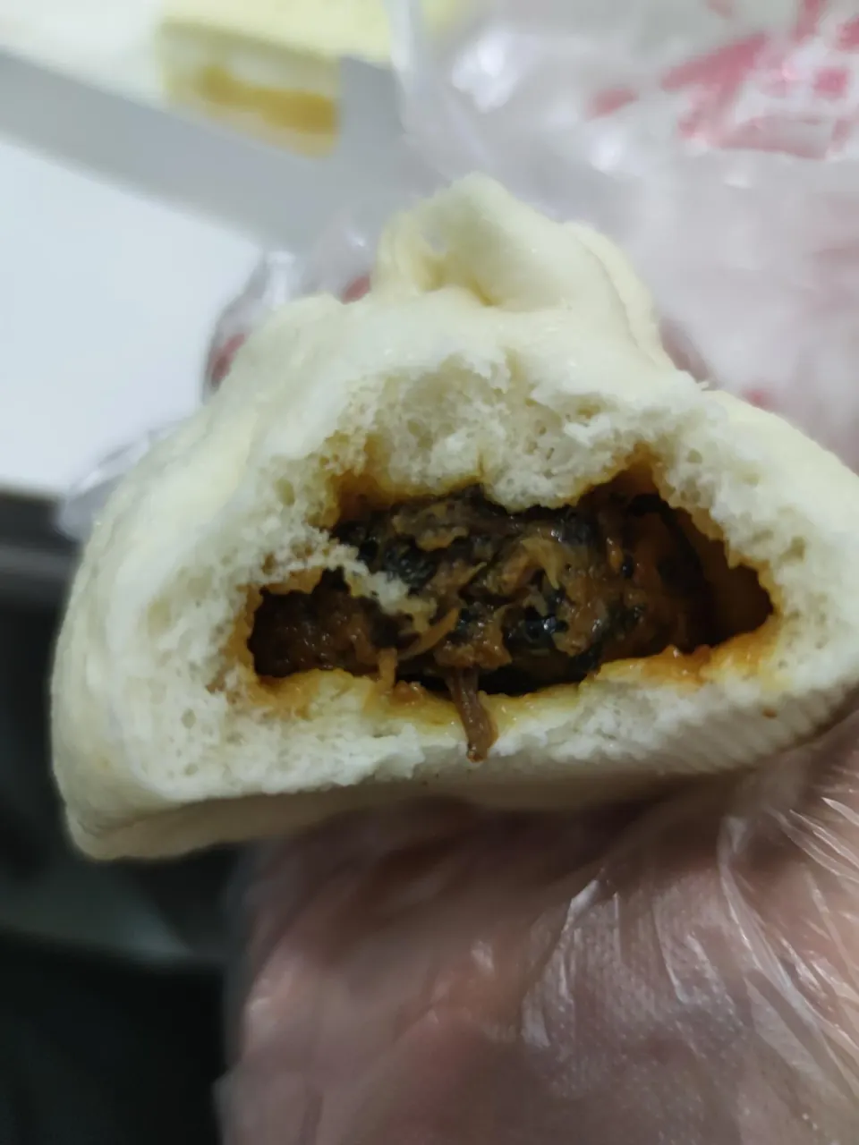 A bitten steamed bun reveals its dark savory filling.