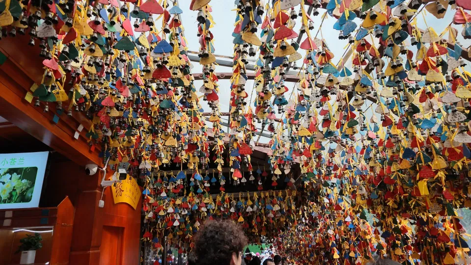 Hundreds of colorful decorative charms hang overhead inside a wooden building.