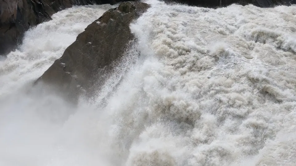 Powerful whitewater surges around a large rock in the gorge.