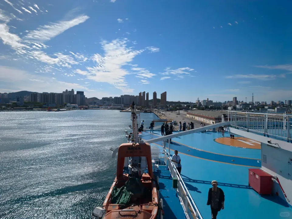 View across the ferry's open deck toward the harbor and waterfront buildings.