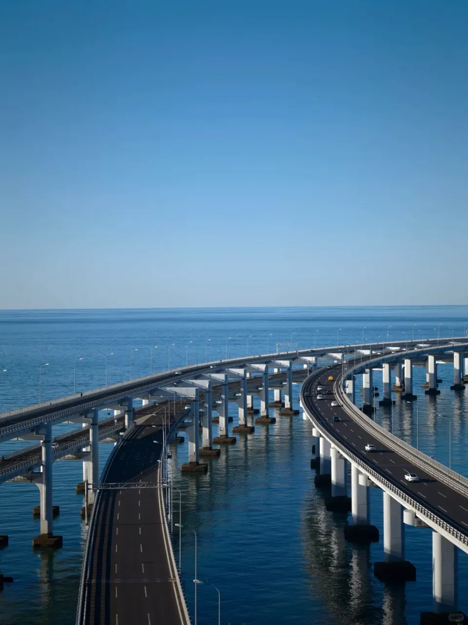 The sea bridge's twin roadways bending over calm blue water.