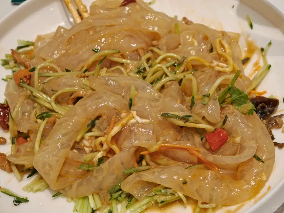 Wide translucent noodles mixed with shredded cucumber and other vegetables.