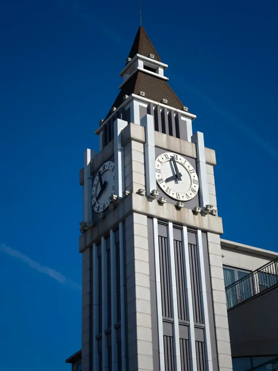 A tall white clock tower beneath a clear blue sky.