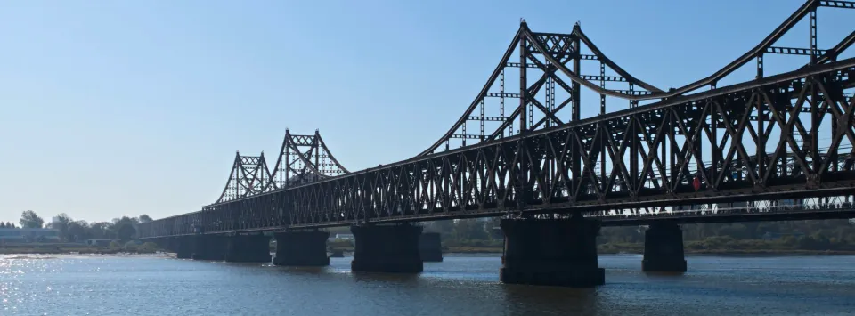 Two steel bridges spanning the blue Yalu River.