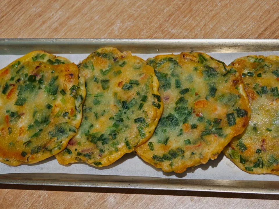 Golden vegetable pancakes arranged on a metal tray.