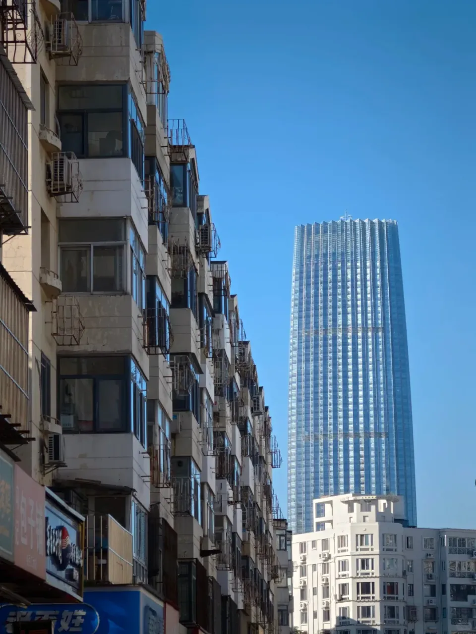 A tall modern tower rising beyond an older apartment building.