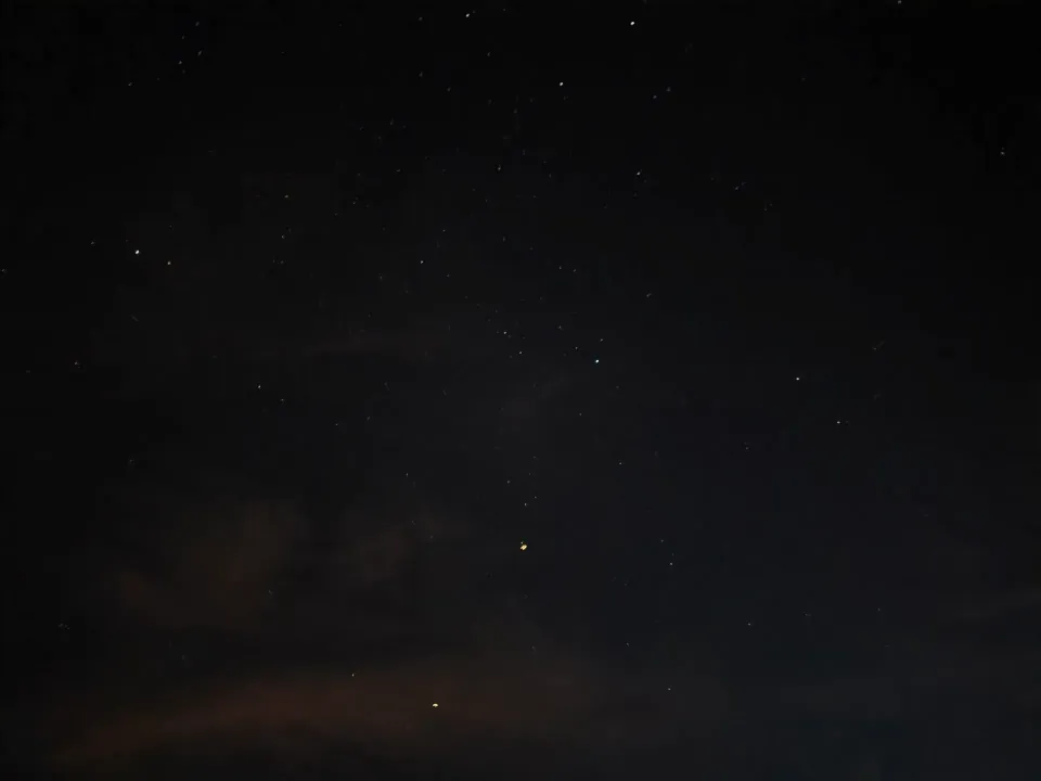 Stars scattered across a dark sky with faint clouds near the horizon.
