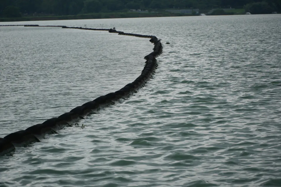 A floating barrier curving across the surface of the lake.