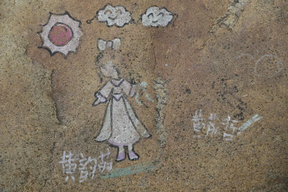 A weathered cartoon drawing painted on a stone.