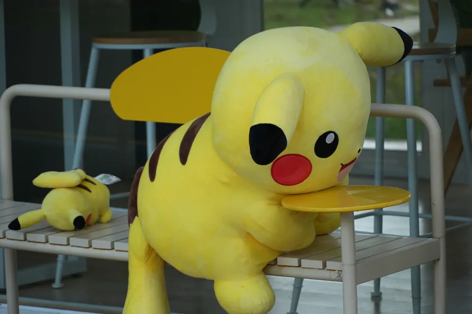 Two large yellow plush toys arranged on outdoor chairs.