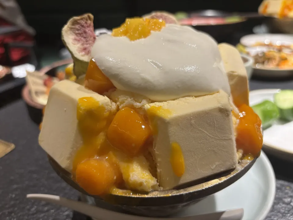 A mango dessert topped with cream and fruit.