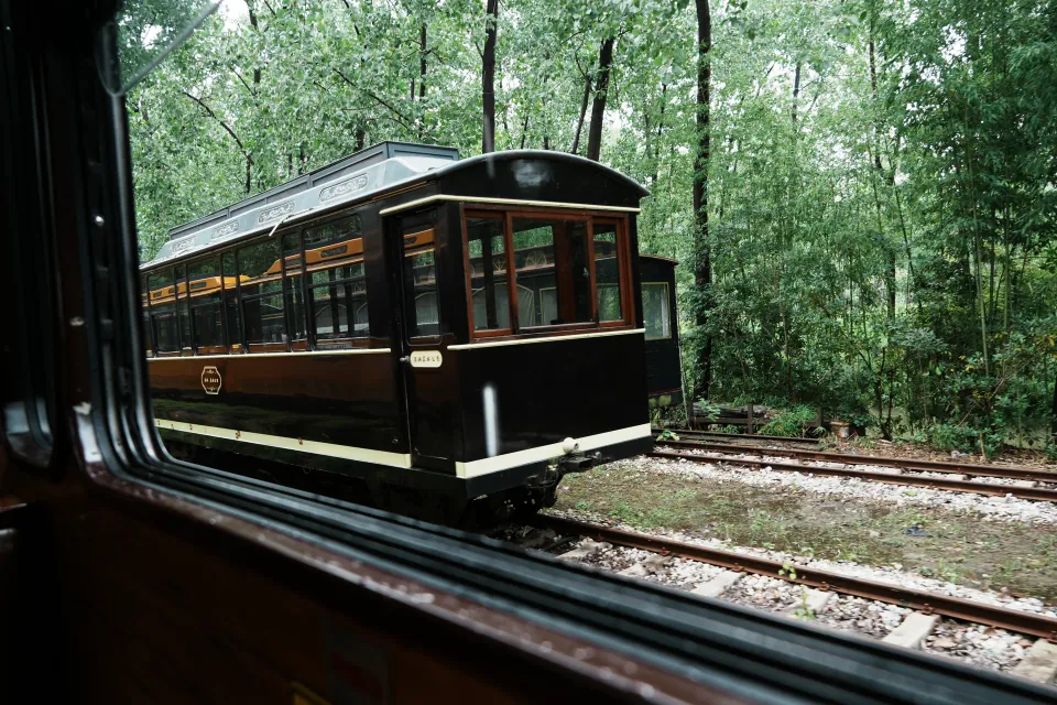 Another vintage train carriage passing on the adjacent track.