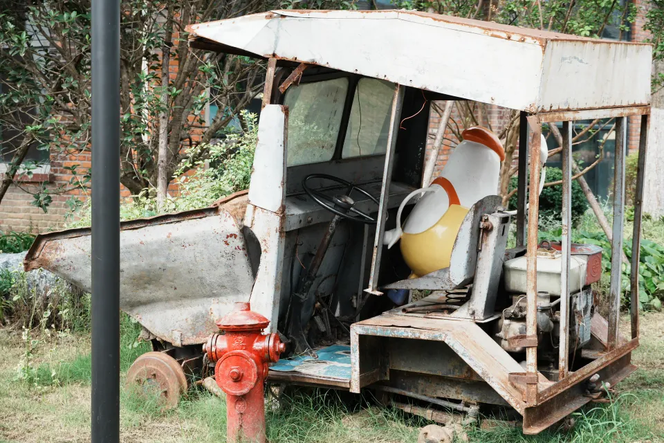 A cartoon figure seated inside a rusted utility vehicle beside a fire hydrant.