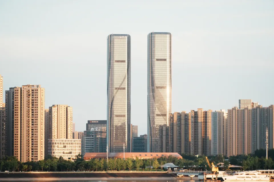 Sunlit glass twin towers on the opposite riverbank