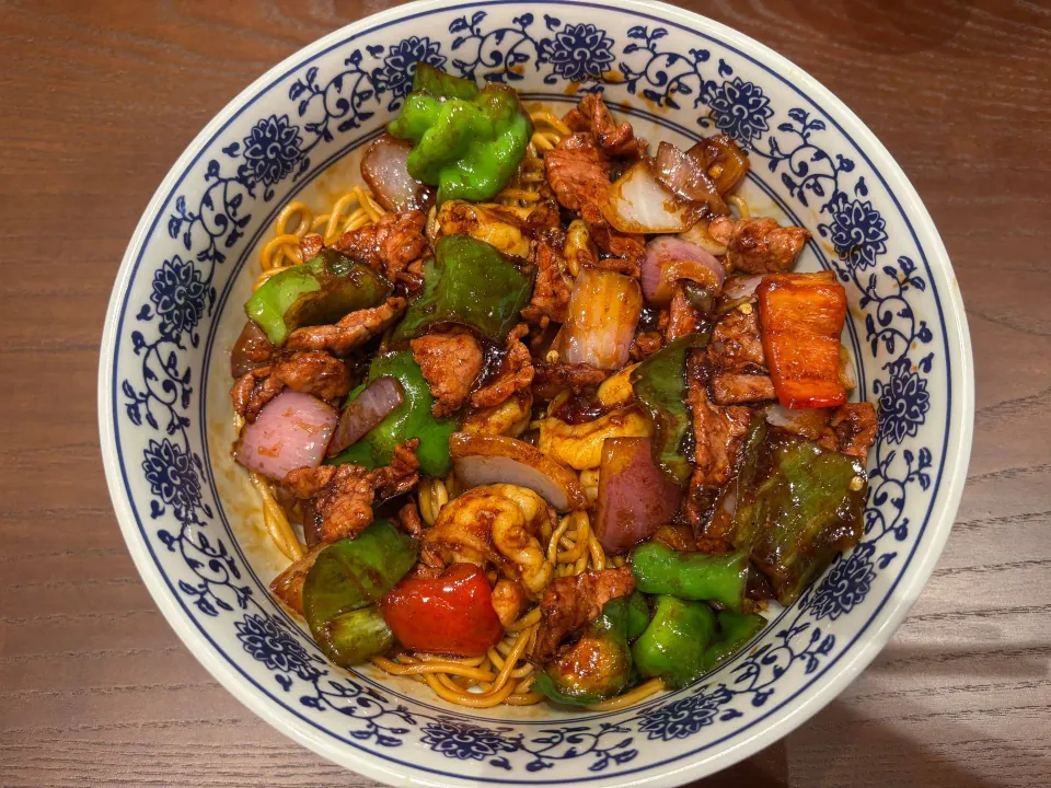 Bowl of shrimp and beef noodles with peppers and onions