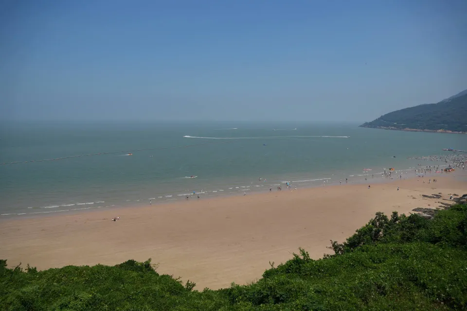Wide sandy beach curving beneath green hills on Liandao