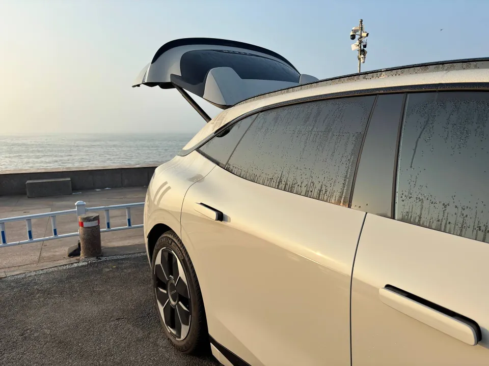 Dew-covered white Zeekr parked beside the sea