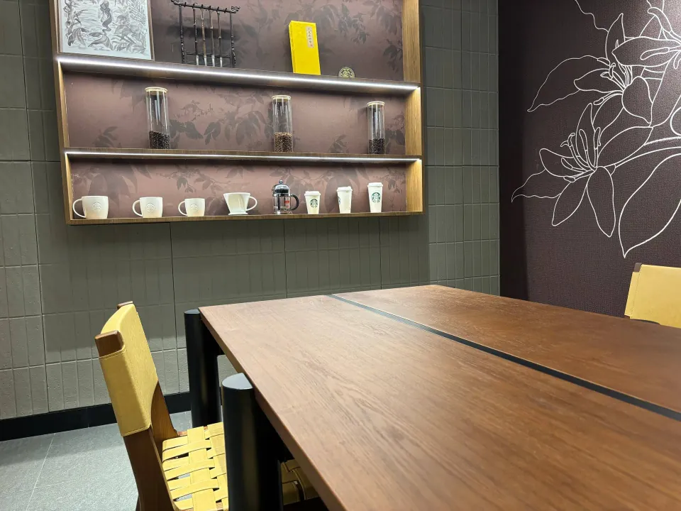 Wooden communal table beneath a shelf of coffee cups