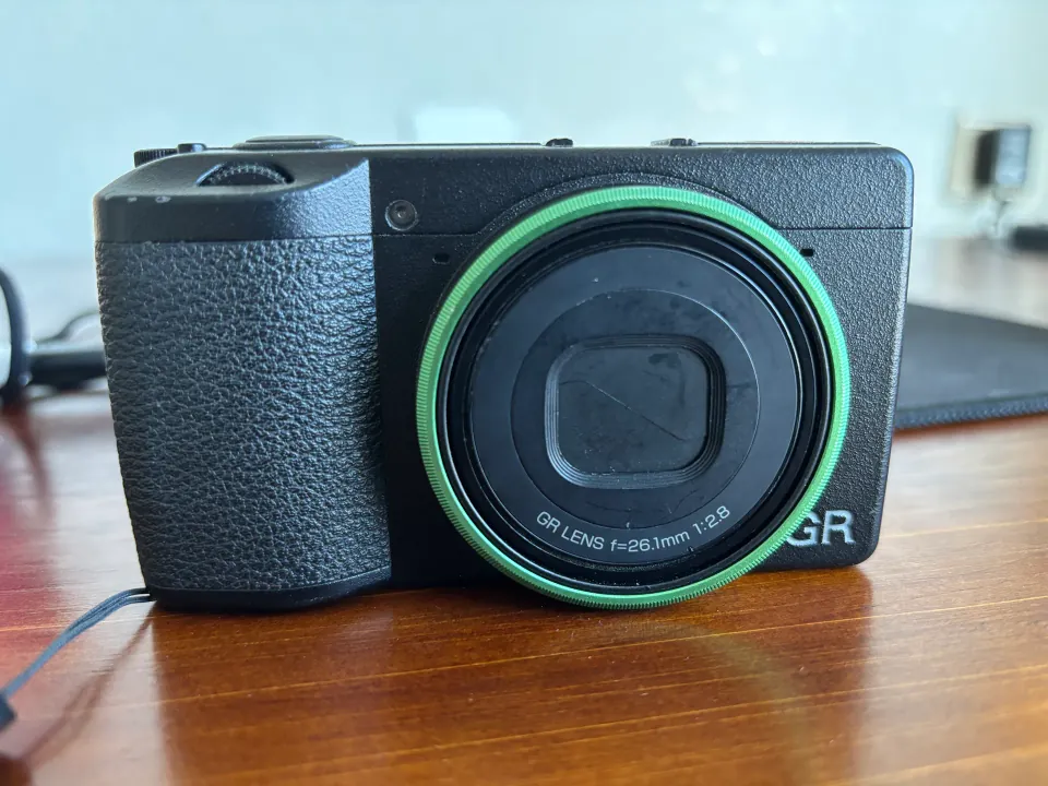 Close-up of a black Ricoh GR IIIx camera with a green lens ring
