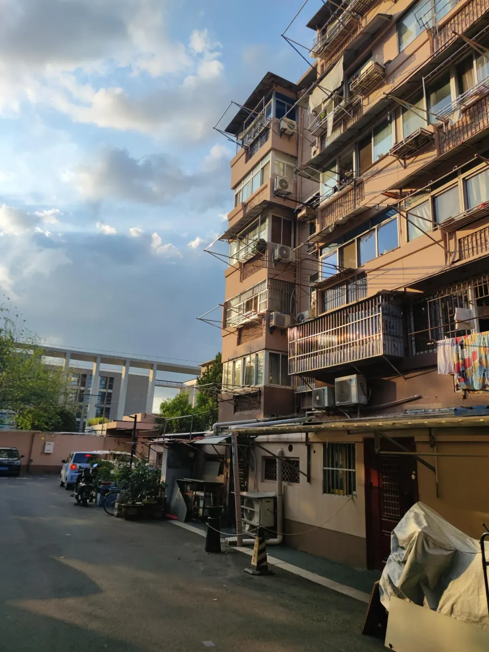 An older apartment building lines a narrow residential lane.