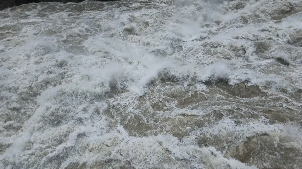 A close view of churning gray-green water and white foam.