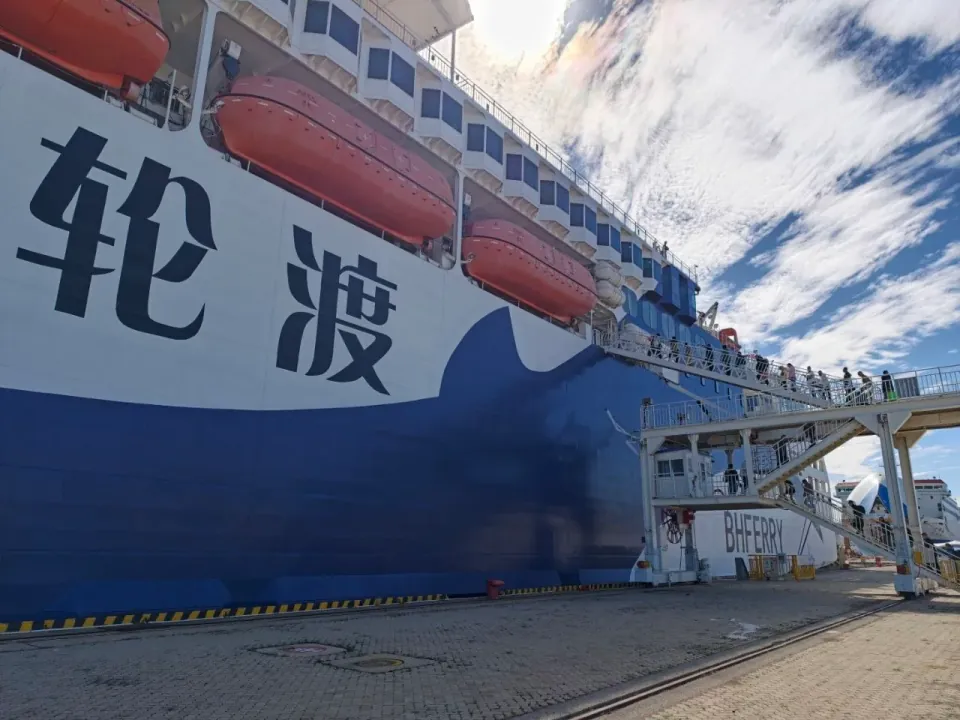Boarding ramp beside a large blue-and-white passenger ferry.