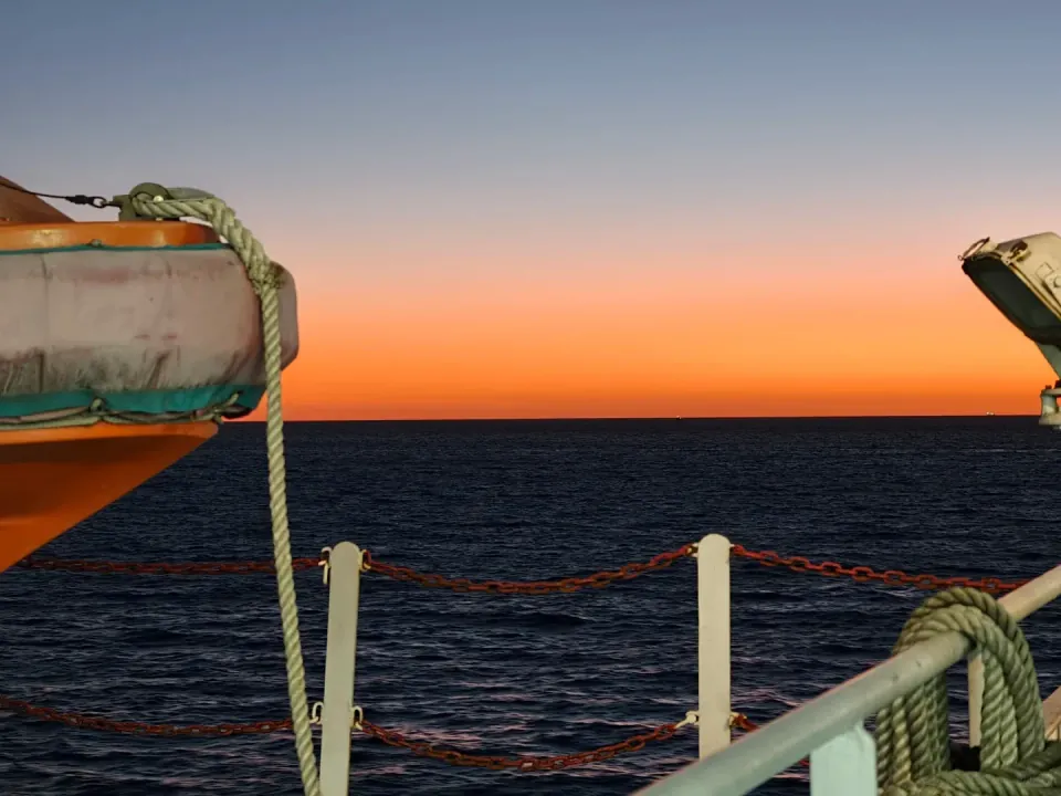 Ferry railings and ropes framing the orange evening horizon.