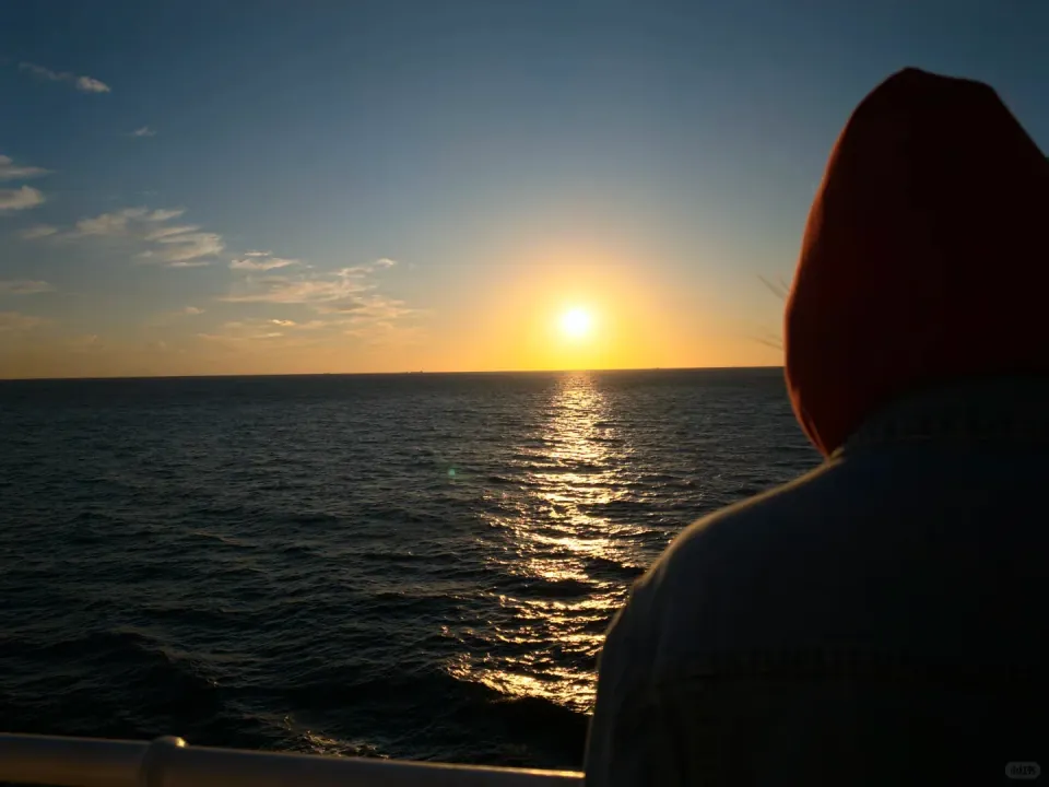 A passenger watching the sun sink toward the sea from the ferry.
