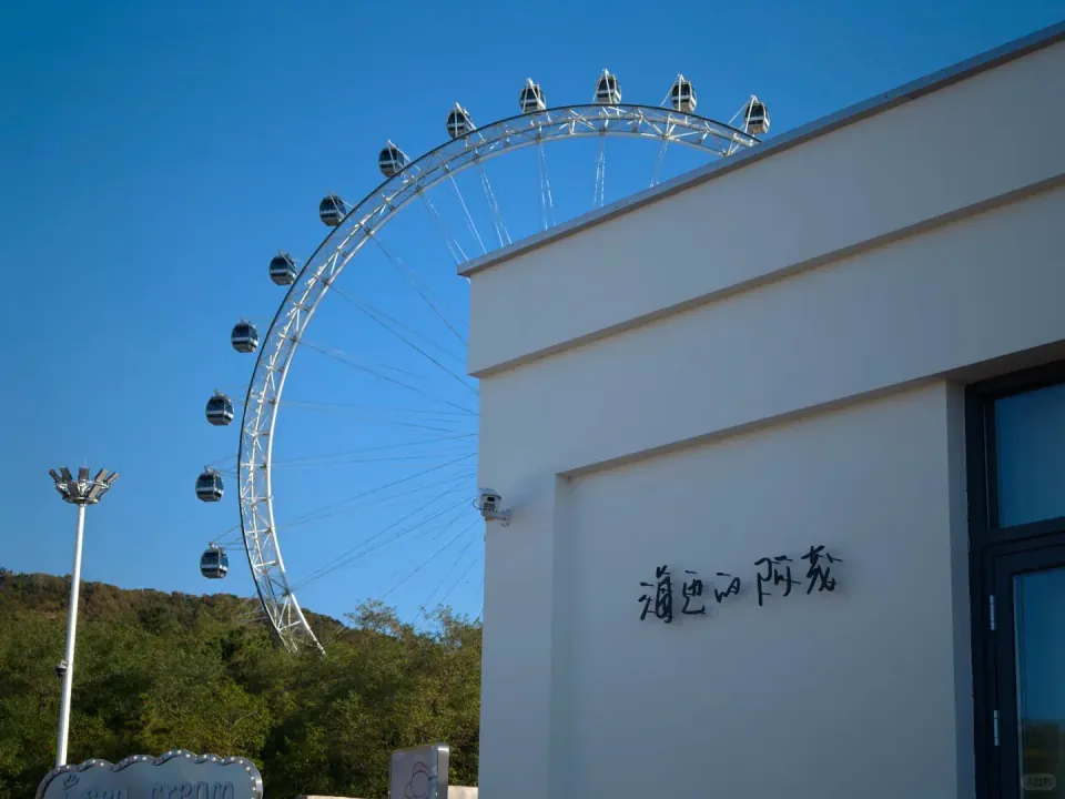 A large Ferris wheel rising behind a white building.