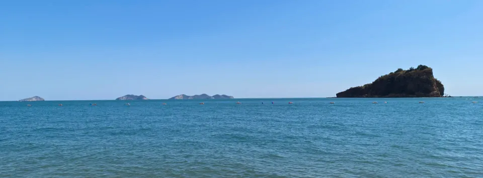 A small rocky island surrounded by bright blue water.