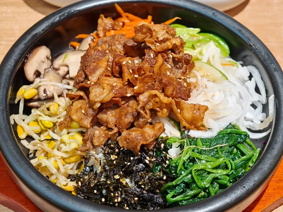 A rice bowl topped with meat, vegetables, and shredded seaweed.