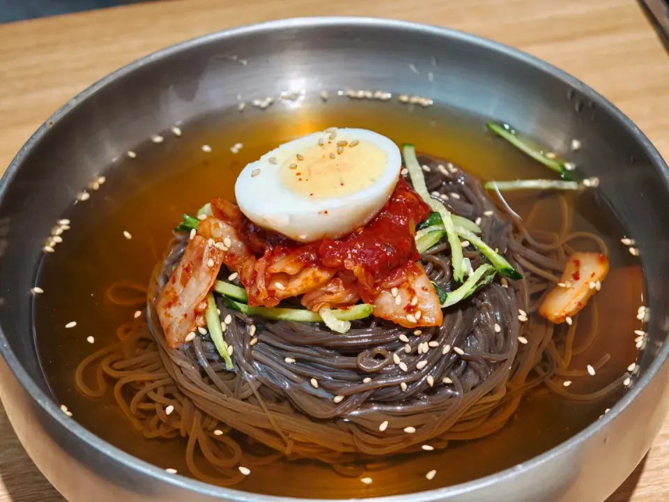 Cold noodles in broth with egg, cucumber, and kimchi.