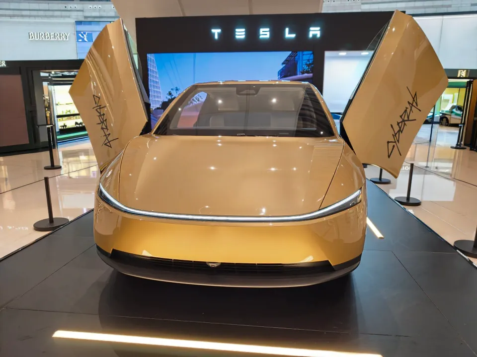 Front view of the gold Tesla Cybercab with its doors raised.