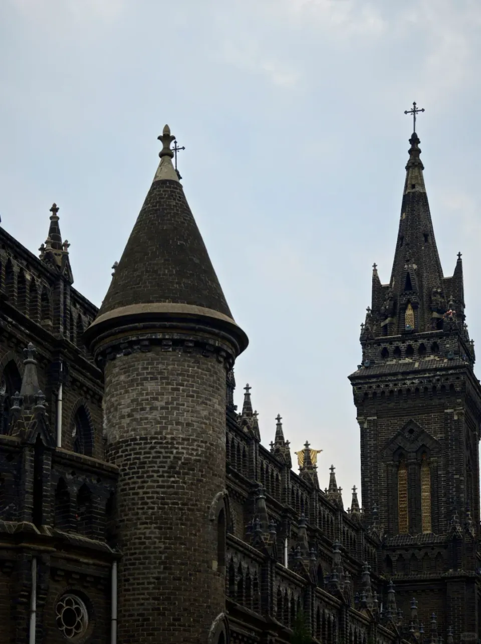 Dark stone church towers beneath a cloudy sky.
